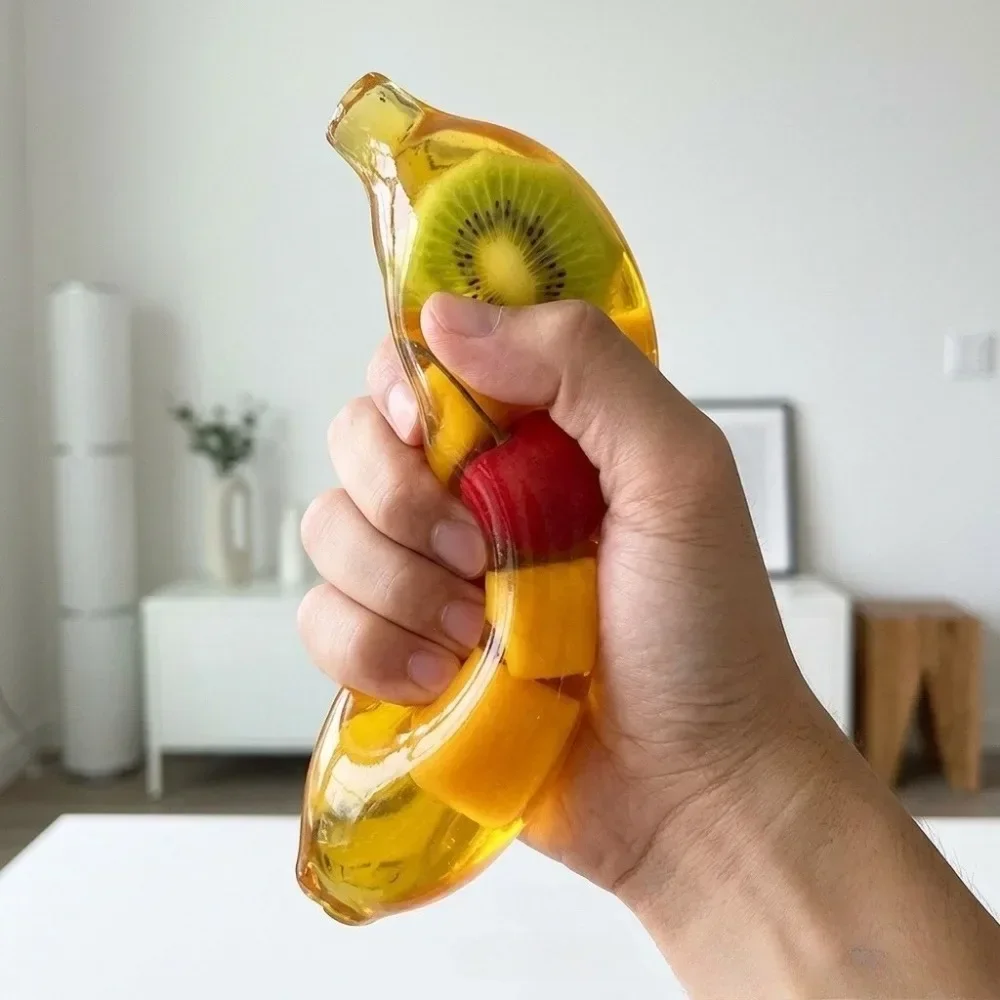 Baby Food Banana - 柔らかいバナナ型のモールト入り、ゆっくりと膨らむ、指先で遊べるおもちゃ。ストレス解消に。中にはフルーツが入っています。子供から大人まで楽しめる、感覚刺激を目的としたプレゼント。